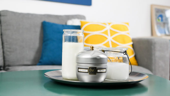 salon avec bougies en premier plan et canapé et coussins jaune et bleu en arrière plan