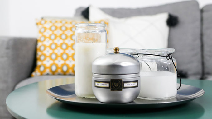 salon avec bougies en premier plan et canapé et coussins jaune et blanc en arrière plan